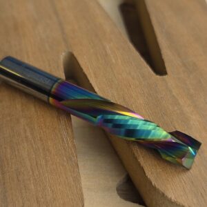 Close-up of a rainbow-colored titanium-coated drill bit resting on a wooden work surface, showing its twisted flutes.