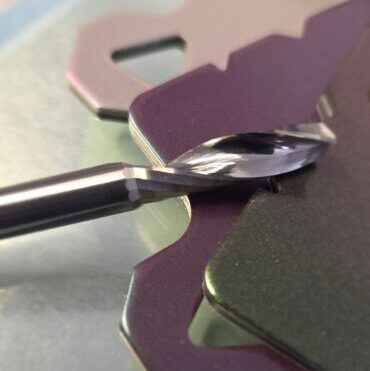 Close-up of a shiny curved blade with purple metal pieces on a reflective surface, macro shot (industrial/tooling context).